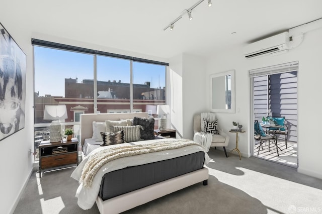 bedroom with a wall mounted air conditioner, track lighting, and dark carpet