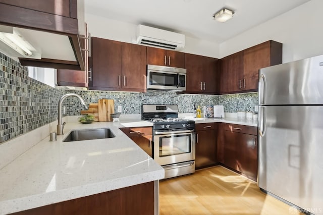 kitchen with sink, tasteful backsplash, a wall mounted AC, appliances with stainless steel finishes, and light stone countertops