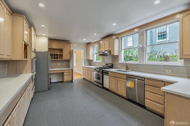 kitchen featuring stainless steel appliances, light brown cabinetry, sink, and backsplash