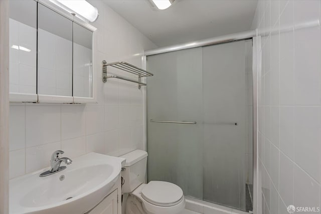 bathroom featuring vanity, a shower with door, and tile walls