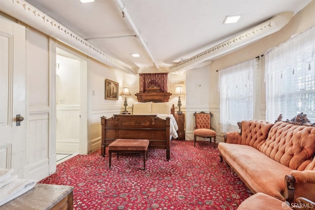 living area with wainscoting, a decorative wall, and carpet
