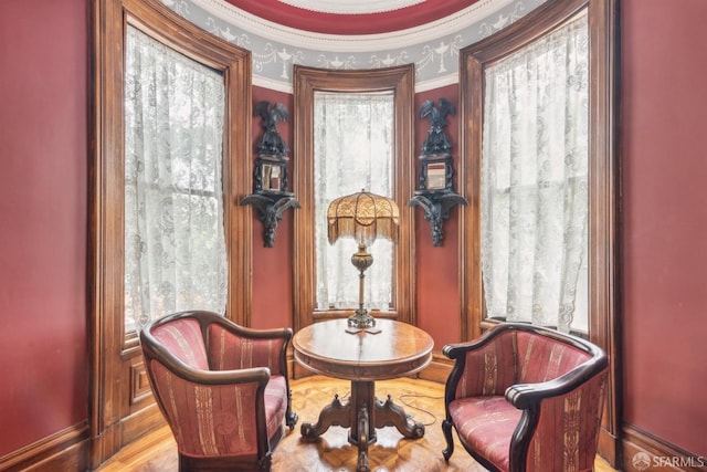 living area with light hardwood / wood-style floors, crown molding, and a healthy amount of sunlight