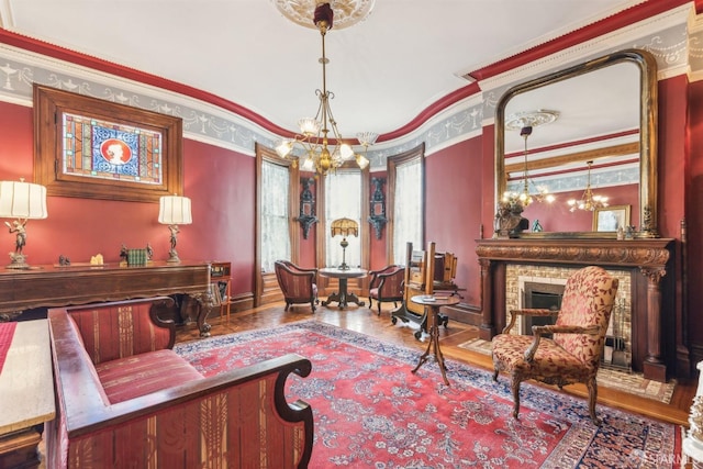 living area with wood finished floors, ornamental molding, and a notable chandelier