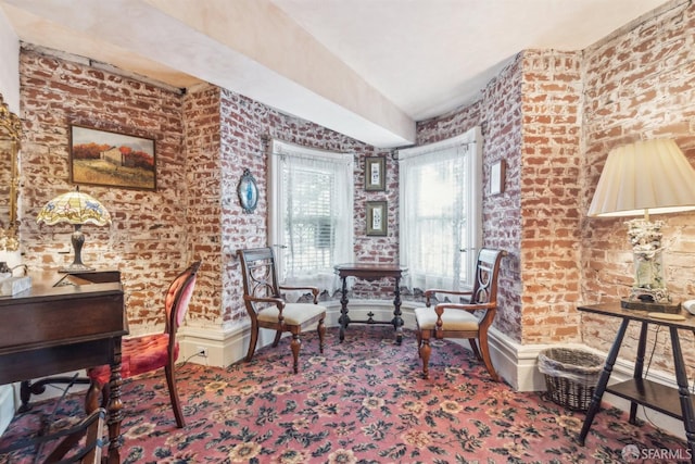 sitting room featuring brick wall and carpet