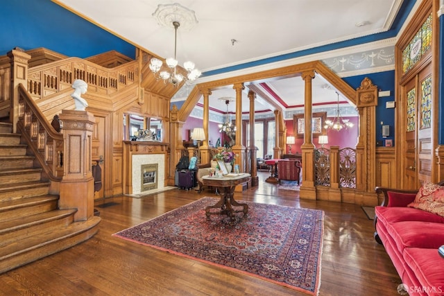 living room with an inviting chandelier, crown molding, dark hardwood / wood-style floors, and ornate columns