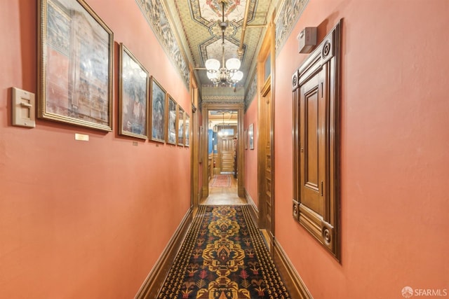 corridor with an inviting chandelier and baseboards