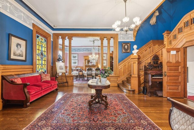 sitting room with a wainscoted wall, wood finished floors, an inviting chandelier, and stairs