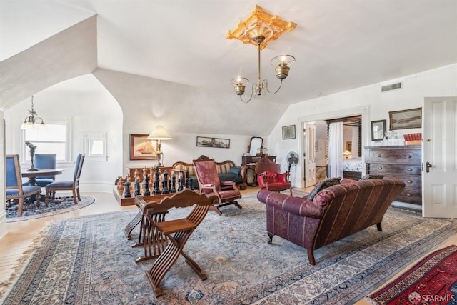 living area featuring vaulted ceiling, visible vents, wood finished floors, and a notable chandelier