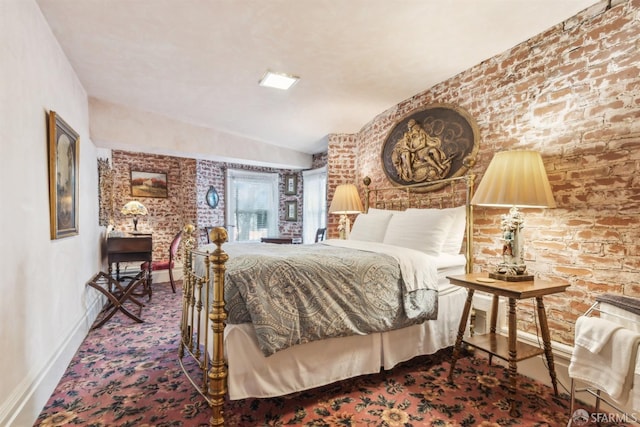 carpeted bedroom with brick wall and baseboards