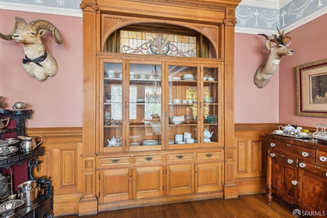 interior space with wainscoting, wood finished floors, and ornamental molding