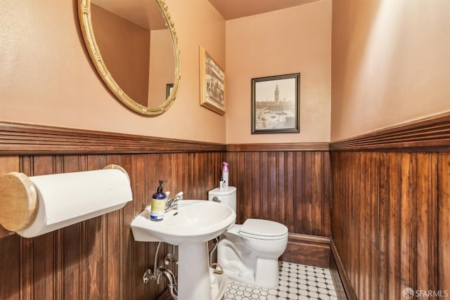 bathroom with toilet, wood walls, and a wainscoted wall