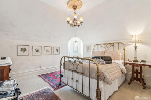 bedroom featuring arched walkways, wood finished floors, lofted ceiling, and a notable chandelier