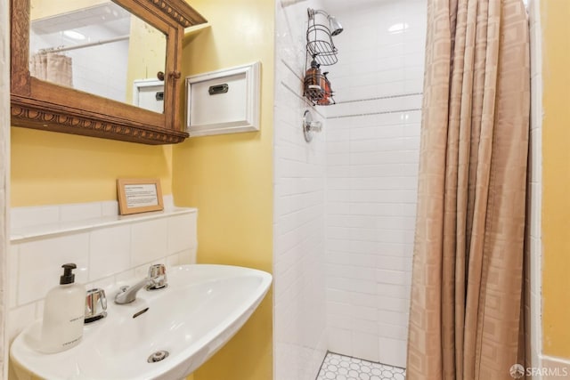 bathroom with sink, a shower with shower curtain, backsplash, and tile patterned flooring