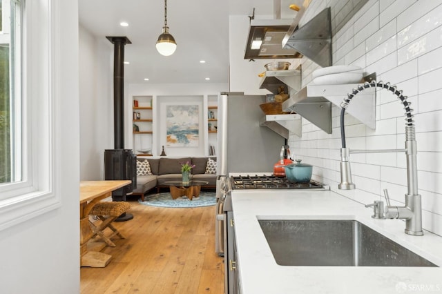 837 Union St, San Francisco, CA 94133 - kitchen with decorative backsplash, light countertops, light wood finished floors, a wood stove, and a sink