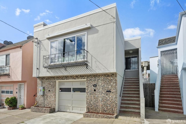 view of property with stucco siding, driveway, and stairs