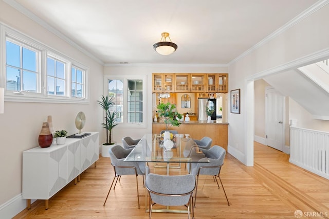 dining area with ornamental molding and light hardwood / wood-style flooring