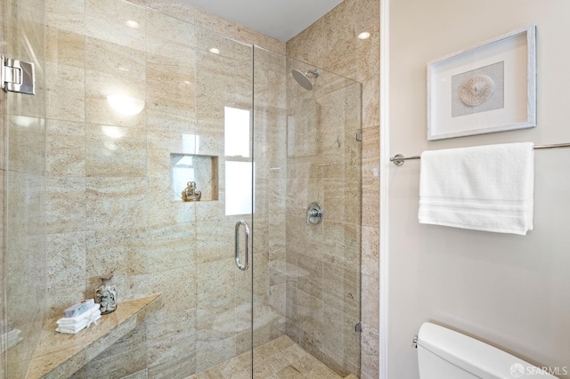 bathroom with a shower with shower door and toilet