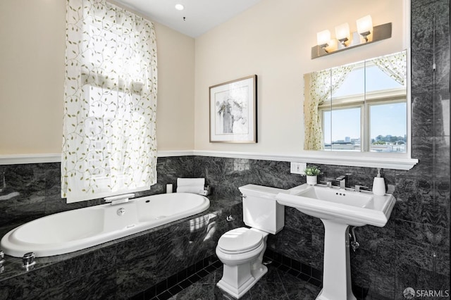 bathroom with a relaxing tiled tub, tile patterned floors, tile walls, and toilet