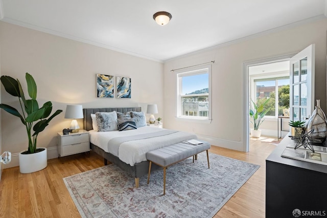 bedroom featuring ornamental molding, light hardwood / wood-style floors, and multiple windows