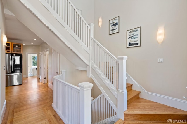 stairway featuring a towering ceiling and hardwood / wood-style floors