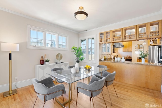 dining space featuring ornamental molding, sink, and light hardwood / wood-style floors