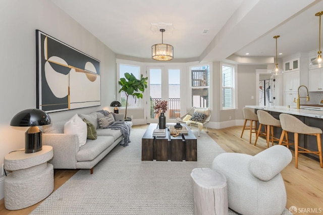 living room featuring a notable chandelier, sink, and light wood-type flooring