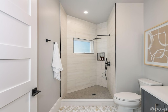 bathroom featuring vanity, toilet, tile patterned floors, and tiled shower