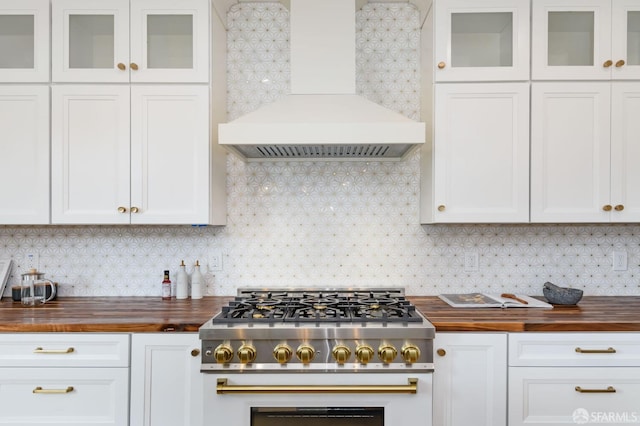 kitchen with high end range, custom range hood, tasteful backsplash, and wood counters