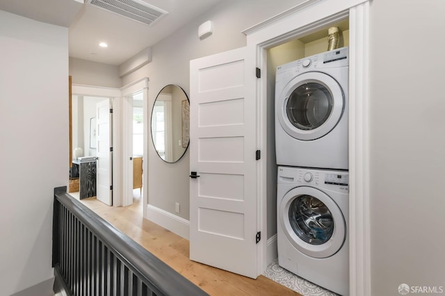 clothes washing area with stacked washer / drying machine and hardwood / wood-style flooring