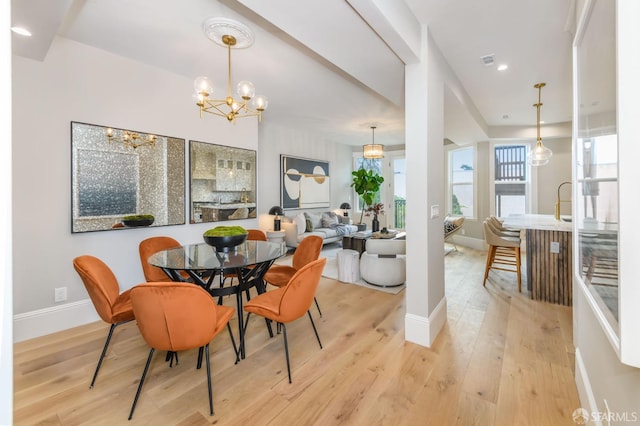 dining space with light hardwood / wood-style flooring and a chandelier