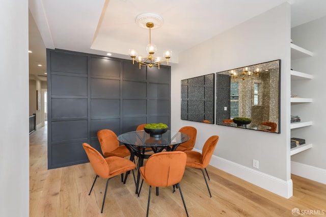 dining area with a notable chandelier, built in shelves, and light wood-type flooring