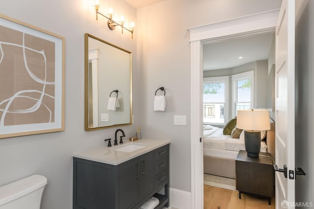 bathroom with toilet, vanity, and wood-type flooring