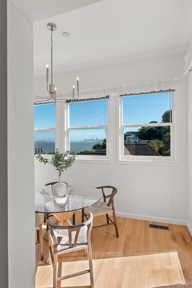 dining area featuring a water view, a notable chandelier, and light hardwood / wood-style flooring