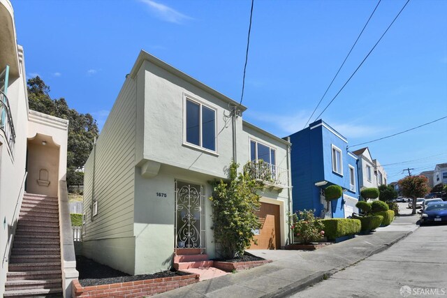 1675 Quint St, San Francisco, CA 94124 - view of front of house with stucco siding, an attached garage, and stairs