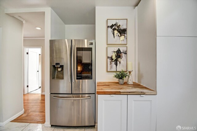 1675 Quint St, San Francisco, CA 94124 - kitchen featuring stainless steel fridge, butcher block counters, white cabinets, recessed lighting, and baseboards