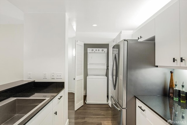 kitchen with white cabinets, stacked washer / dryer, sink, and dark hardwood / wood-style flooring