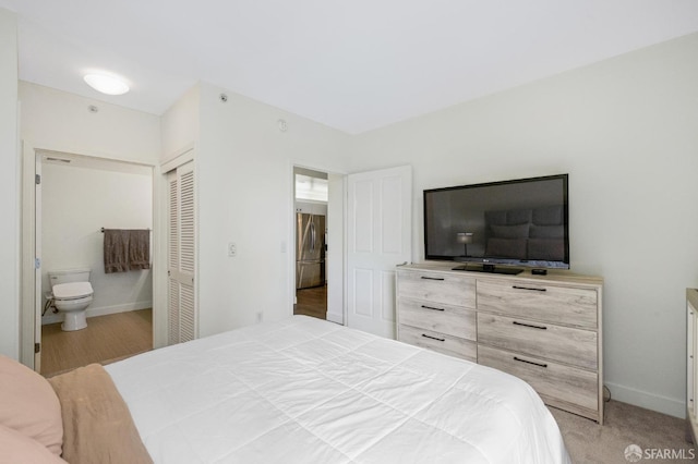 bedroom featuring light colored carpet, a closet, and ensuite bathroom