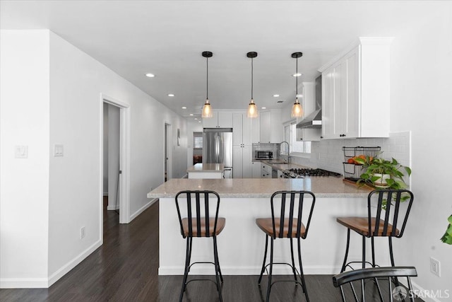 kitchen featuring appliances with stainless steel finishes, pendant lighting, a breakfast bar area, white cabinets, and kitchen peninsula