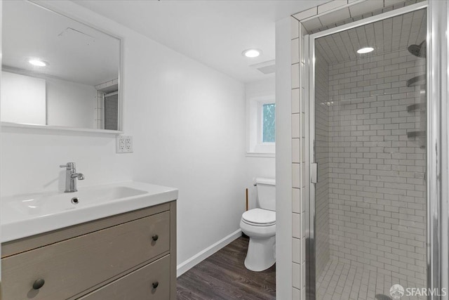 bathroom with hardwood / wood-style flooring, vanity, toilet, and a shower with shower door