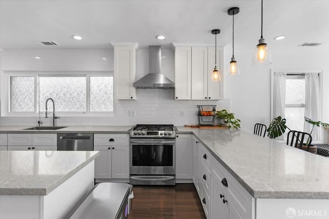 kitchen featuring appliances with stainless steel finishes, sink, white cabinets, and wall chimney exhaust hood