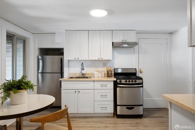 1141 Church St, San Francisco, CA 94114 - kitchen featuring appliances with stainless steel finishes, a sink, under cabinet range hood, white cabinets, and light wood-style flooring