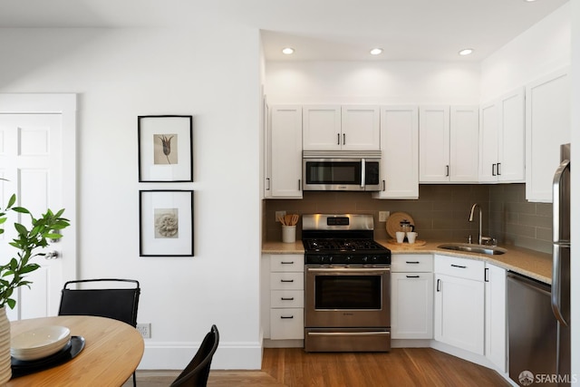 1141 Church St, San Francisco, CA 94114 - kitchen with stainless steel appliances, a sink, backsplash, wood finished floors, and white cabinets
