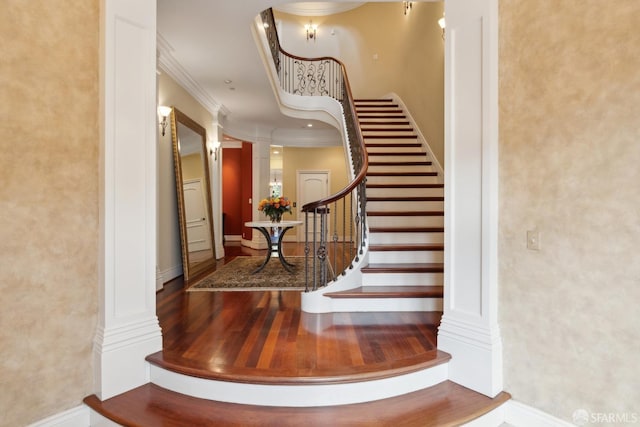 stairway with crown molding and ornate columns