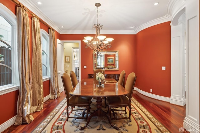 dining space featuring hardwood / wood-style flooring, crown molding, and an inviting chandelier