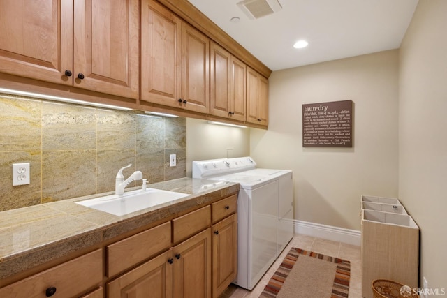 clothes washing area with cabinets, sink, light tile patterned floors, and washing machine and clothes dryer