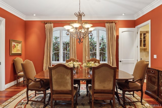 dining area with ornamental molding, hardwood / wood-style floors, and an inviting chandelier