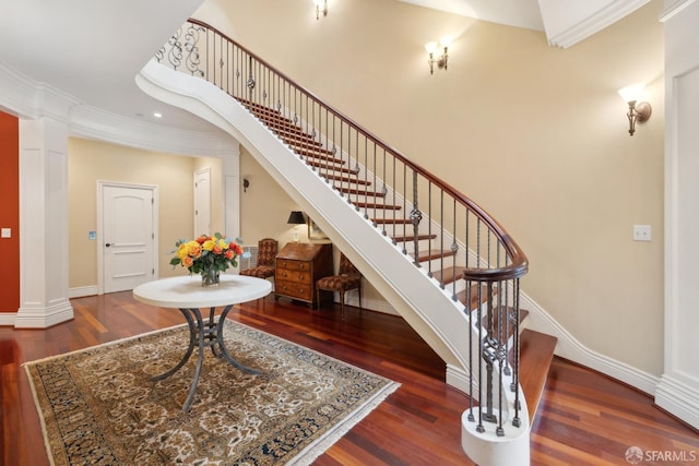 entrance foyer featuring dark wood-type flooring, ornamental molding, and decorative columns