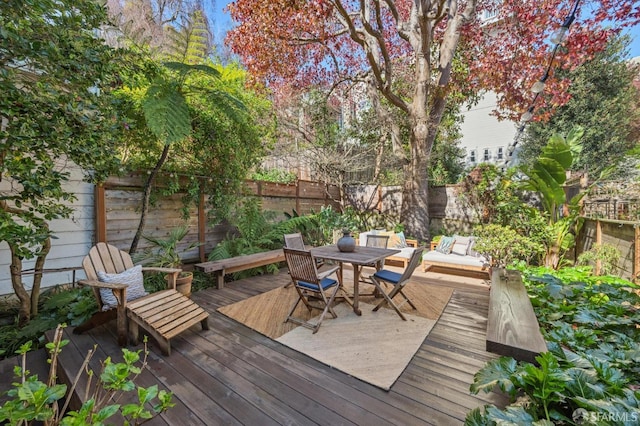 wooden terrace with outdoor dining area and a fenced backyard