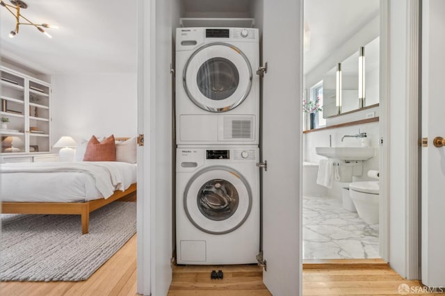 washroom with a sink, wood finished floors, and stacked washing maching and dryer