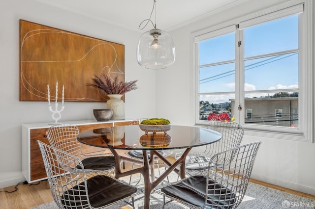 dining space with baseboards, light wood-style floors, and crown molding